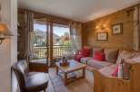 Experience cozy mountain living in this charming living room featuring warm wood paneling and a comfortable sectional sofa adorned with red accent pillows.