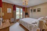 Experience serene mountain living in this charming bedroom featuring warm wood paneling and a private balcony with breathtaking views.