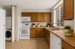 Discover this charming kitchen featuring warm oak cabinetry and a convenient stacked washer and dryer.