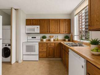 Discover this charming kitchen featuring warm oak cabinetry and a convenient stacked washer and dryer.