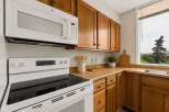 This charming kitchen features warm oak cabinetry complemented by a sleek white microwave and range.