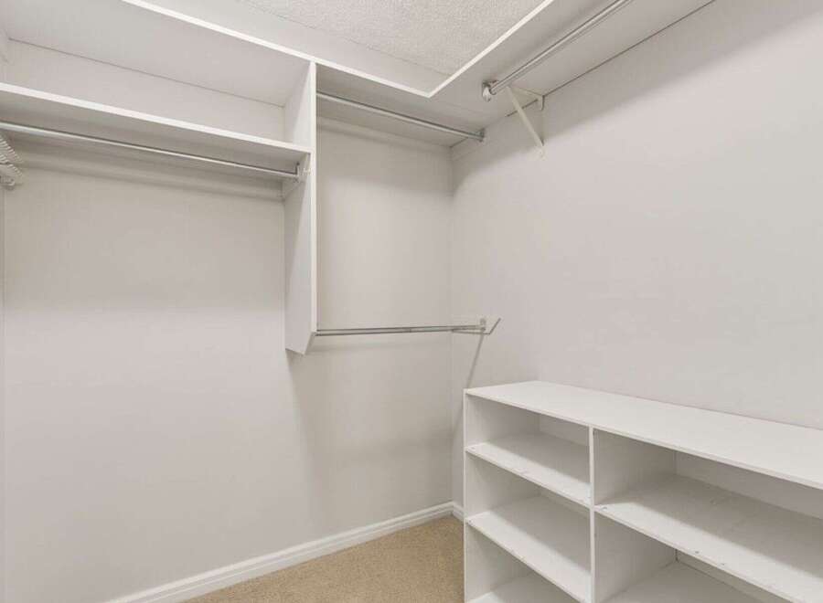 Discover ample storage in this spacious walk-in closet, featuring multiple hanging rods and shelving units.