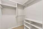 Discover ample storage in this spacious walk-in closet, featuring multiple hanging rods and shelving units.