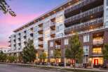 Experience modern urban living in this stunning multi-story apartment building, featuring sleek architecture and private balconies perfect for enjoying the twilight sky.