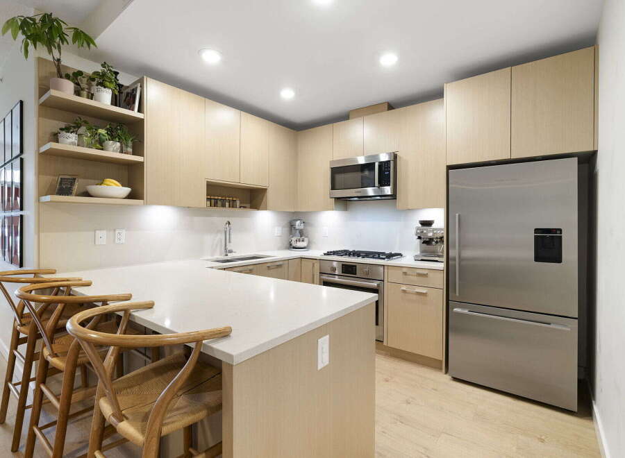 Experience modern living in this stunning kitchen, featuring sleek light wood cabinetry and a spacious quartz island perfect for entertaining.
