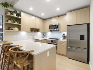 Experience modern living in this stunning kitchen, featuring sleek light wood cabinetry and a spacious quartz island perfect for entertaining.