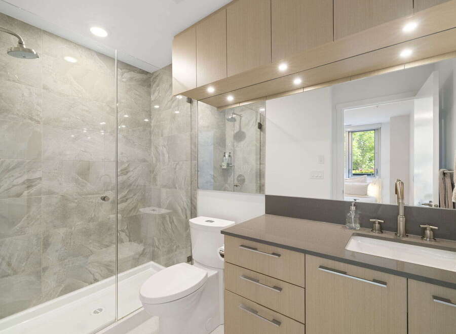 Experience modern luxury in this stunning bathroom featuring a spacious walk-in shower with elegant marble-look tiles and a sleek glass enclosure.