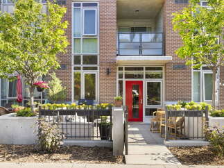 Discover modern urban living in this stunning condo featuring a vibrant red front door and a private patio area perfect for outdoor relaxation.