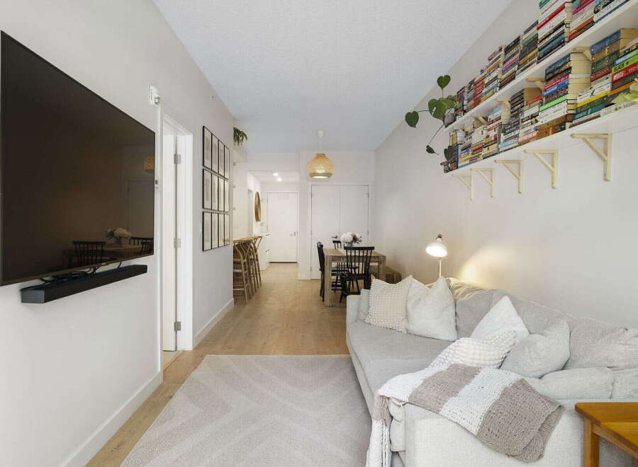 This modern living space features a large wall-mounted TV and a comfortable grey sofa adorned with plush pillows and a cozy throw blanket.