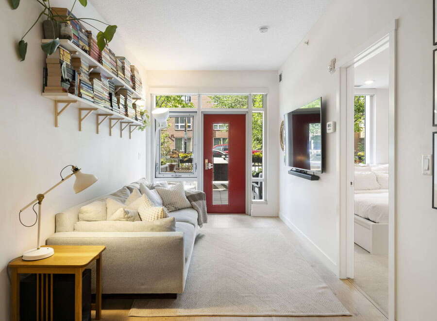 Bright and airy living space featuring a comfortable sofa, a stylish floor lamp, and ample storage with wall-mounted bookshelves.