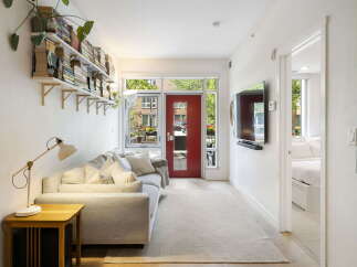 Bright and airy living space featuring a comfortable sofa, a stylish floor lamp, and ample storage with wall-mounted bookshelves.