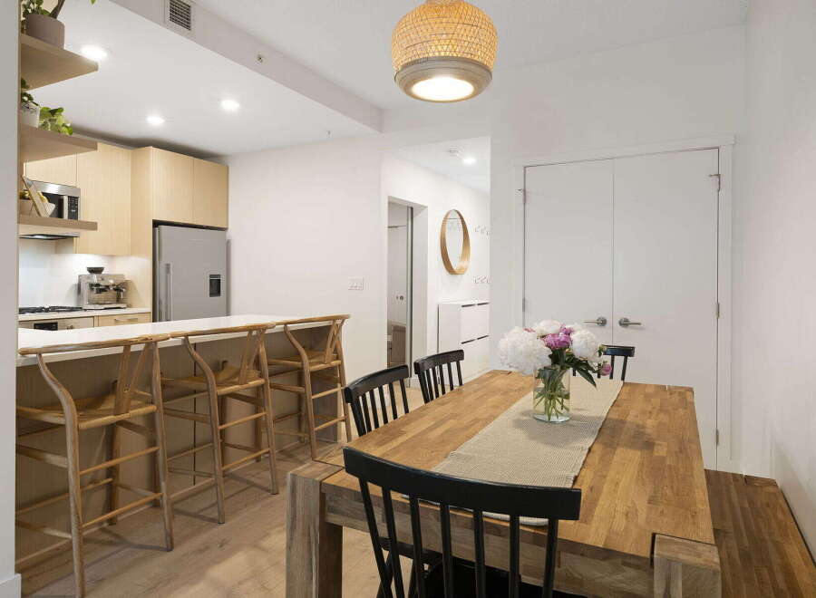 This modern dining area features a spacious wooden table with black chairs, perfect for family meals.