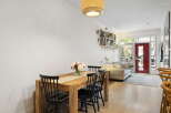Bright and airy open-concept living space featuring a modern dining area with a wooden table and chairs, adjacent to a comfortable living room with a plush sofa.
