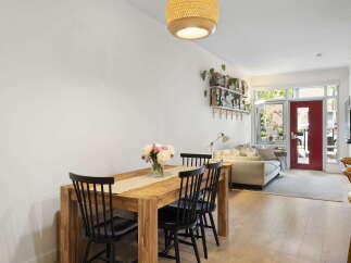 Bright and airy open-concept living space featuring a modern dining area with a wooden table and chairs, adjacent to a comfortable living room with a plush sofa.