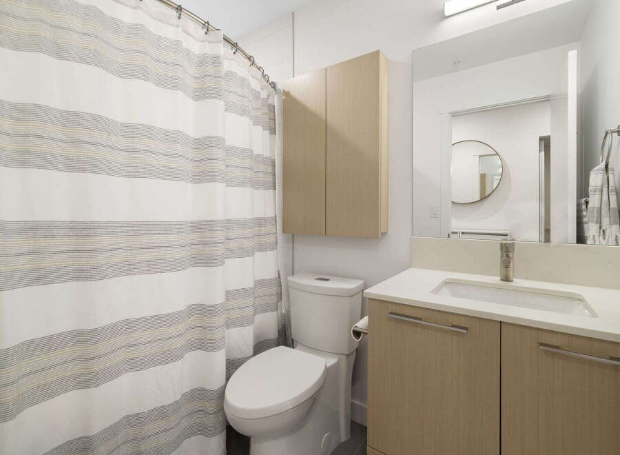 This modern bathroom features a clean white toilet next to a stylish shower curtain with subtle stripes.