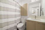 This modern bathroom features a clean white toilet next to a stylish shower curtain with subtle stripes.
