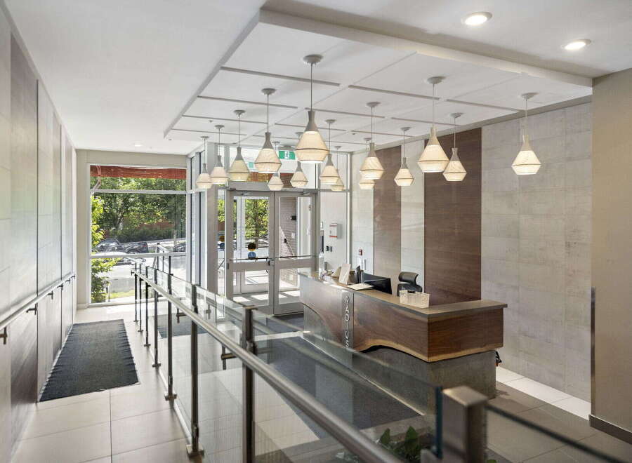 Step into a welcoming lobby featuring a modern reception desk with a live edge wood counter and elegant pendant lighting.