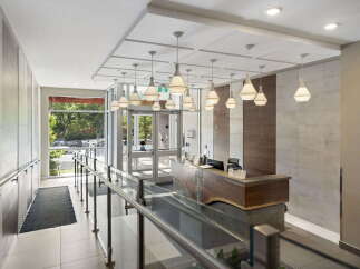 Step into a welcoming lobby featuring a modern reception desk with a live edge wood counter and elegant pendant lighting.