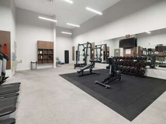 This modern gym features a comprehensive selection of free weights, including a full dumbbell rack, and a variety of cardio machines like treadmills.