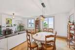 This spacious living and dining area features a cozy fireplace, a comfortable white sofa, and a charming round dining table perfect for family meals.
