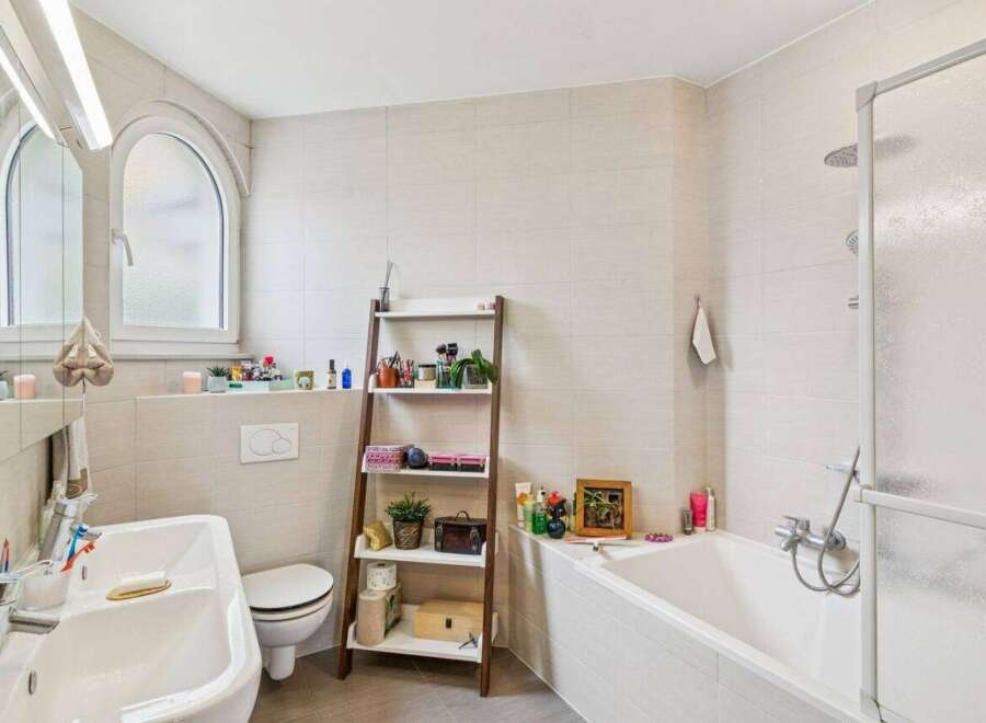 This modern bathroom features a clean and bright aesthetic with light-colored tiled walls and floors.