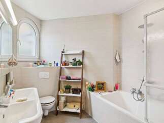 This modern bathroom features a clean and bright aesthetic with light-colored tiled walls and floors.