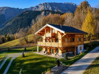 Experience the charm of this stunning wooden chalet nestled amidst the breathtaking autumn scenery of the Alps.