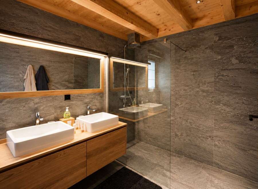 Experience modern luxury in this stunning bathroom featuring a double vanity with sleek rectangular sinks and a spacious walk-in shower with elegant stone tile.