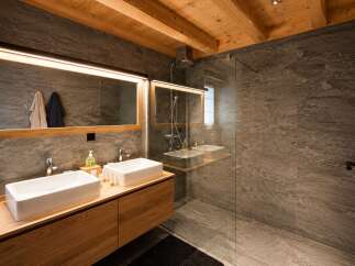 Experience modern luxury in this stunning bathroom featuring a double vanity with sleek rectangular sinks and a spacious walk-in shower with elegant stone tile.