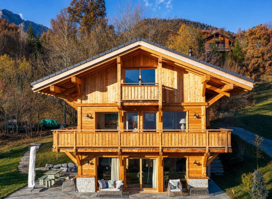 Experience luxury mountain living in this stunning wooden chalet, nestled amidst vibrant autumn foliage.