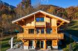 Experience luxury mountain living in this stunning wooden chalet, nestled amidst vibrant autumn foliage.