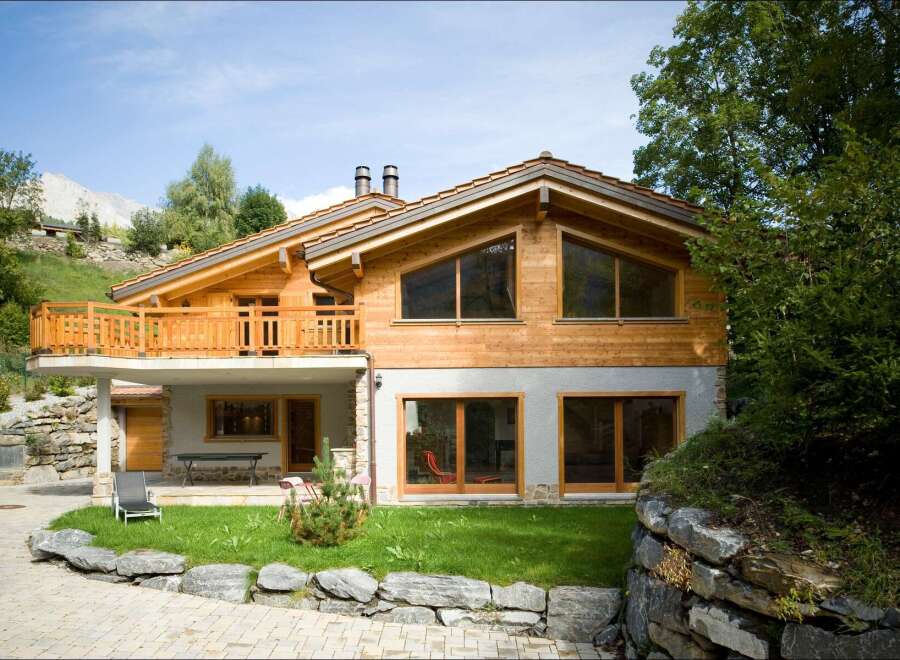 Experience luxury mountain living in this stunning chalet, featuring a spacious wooden balcony with breathtaking views.