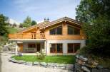 Experience luxury mountain living in this stunning chalet, featuring a spacious wooden balcony with breathtaking views.