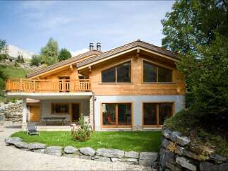Experience luxury mountain living in this stunning chalet, featuring a spacious wooden balcony with breathtaking views.