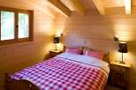 Experience rustic charm in this cozy bedroom, featuring warm wood paneling and exposed beams.
