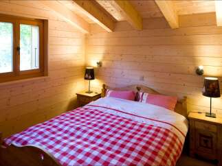Experience rustic charm in this cozy bedroom, featuring warm wood paneling and exposed beams.