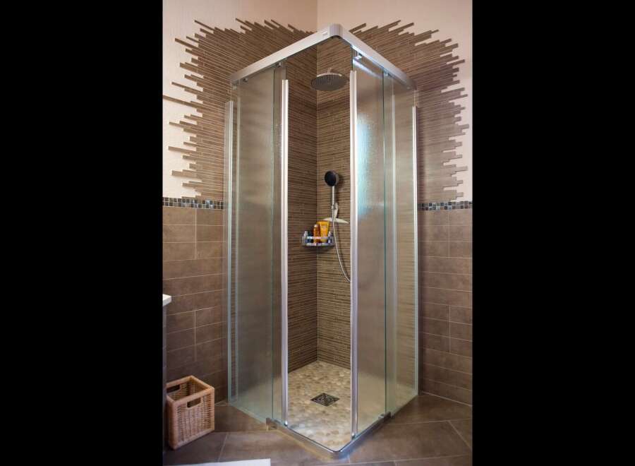 Experience modern luxury in this stunning bathroom featuring a spacious corner shower with frosted glass doors and a sleek chrome frame.