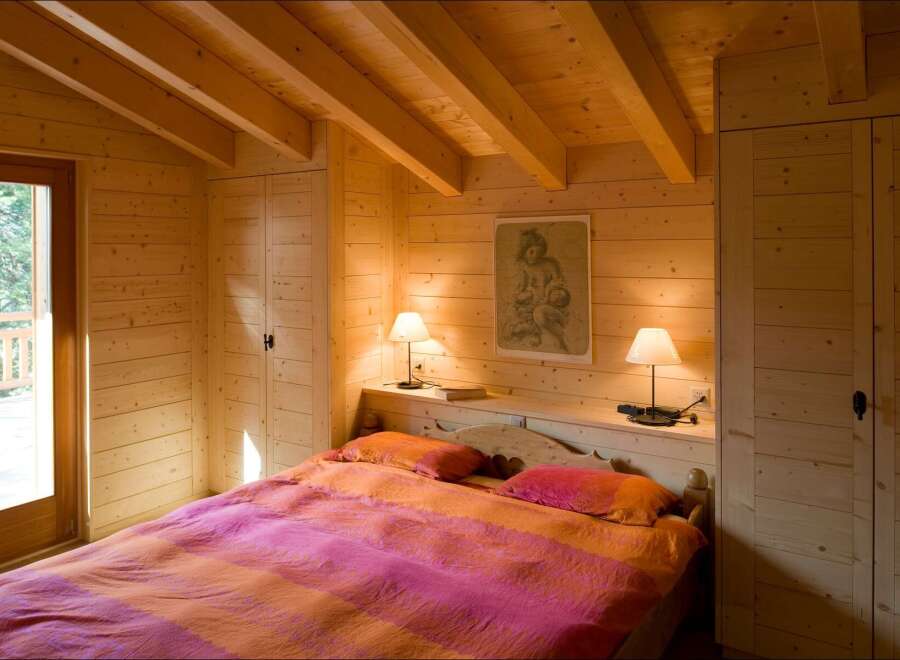 Experience rustic charm in this cozy wooden bedroom, featuring a comfortable bed with vibrant bedding and a beautiful piece of art above the headboard.