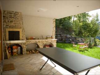 Enjoy outdoor living with this covered patio featuring a stone fireplace and built-in counter space, perfect for entertaining.