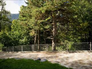 Discover this property featuring a paved driveway leading to a lush green lawn, bordered by a modern metal fence.