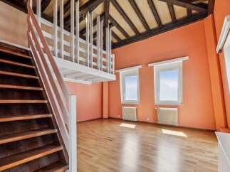 Discover this charming attic space featuring a rustic wooden staircase leading to a loft area with white railings.