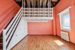 Discover this charming loft space featuring a white railing overlooking the room and a wooden staircase leading to the upper level.