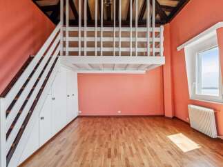Discover this charming loft space featuring a white railing overlooking the room and a wooden staircase leading to the upper level.