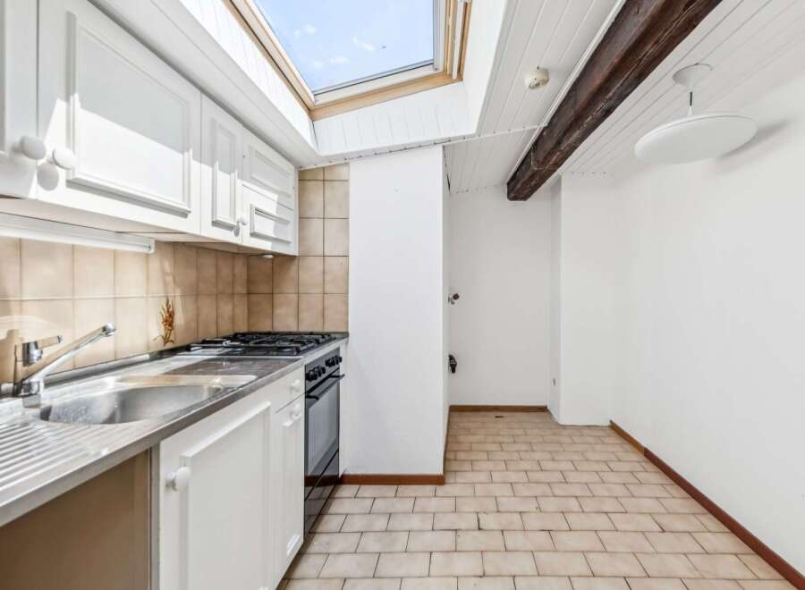 This charming kitchen features white cabinetry and a stainless steel sink, perfect for meal preparation.