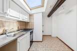 This charming kitchen features white cabinetry and a stainless steel sink, perfect for meal preparation.
