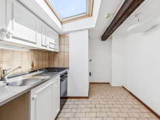 This charming kitchen features white cabinetry and a stainless steel sink, perfect for meal preparation.
