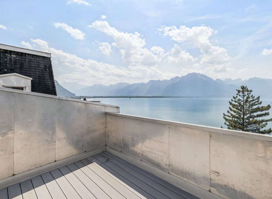 Experience breathtaking panoramic views from this stunning balcony overlooking a serene lake and majestic mountains.
