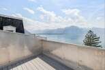 Experience breathtaking panoramic views from this stunning balcony overlooking a serene lake and majestic mountains.