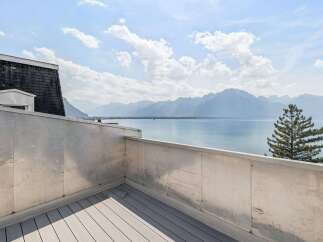Experience breathtaking panoramic views from this stunning balcony overlooking a serene lake and majestic mountains.