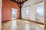 Experience breathtaking mountain views from this spacious room featuring a charming salmon-colored accent wall and a glass door leading to a balcony.
